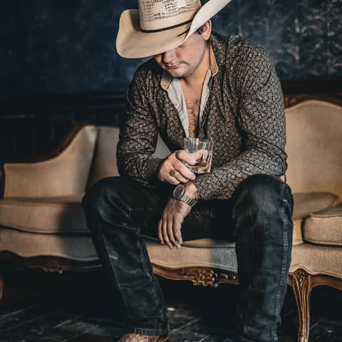 Bryce Beene sitting on a couch, holding a glass of whiskey.